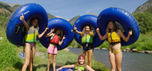 A group of kids enjoying tubing down the Telluride River Trail in the summertime.
